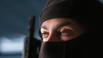 Terrorist hiding identity, attacking enemy command center. Close up of masked insurgent inspecting room during enemy base assault hijacking in guerilla warfare armed conflict, camera A video