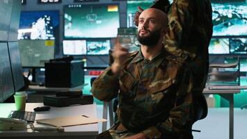 Military agent using augmented reality tech in control room, analyzing aerial reconnaissance data. Intelligence corps expert controlling drones attacking strategic targets using AR hologram, camera A video