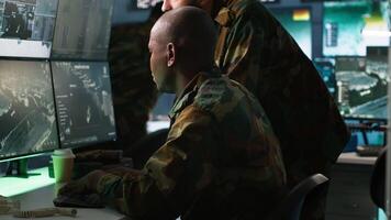 Army telecommunications operators using radio and satellite gear, inputting data on systems. Military dispatchers managing communications networks, typing on keyboard, camera A video