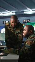 Vertical Military officers look at intel folder files on enemy battle formation, comparing with radar images. Army specialists looking at mission case file and equipment screens, camera B video