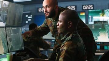 Air force officers performing tactical level reconnaissance in command post, looking at monitors. Military soldiers using radar devices to look at assault zones on displays, camera A video