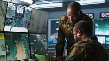 Military officers look at intel folder files on enemy battle formation, comparing with radar images. Army specialists looking at mission case file and equipment screens, camera A video