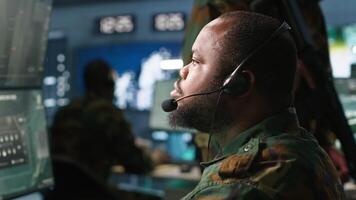 Army telecommunication systems operator using radio and satellite gear, providing combat support. Military dispatcher managing communications networks, looking at screens, camera A video