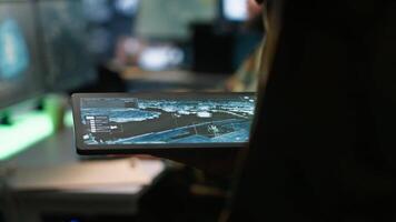 Army operative using tablet in command center housing operational missile defense system designed to intercept ballistic rockets. Close up of expert using tracking software on device, camera A video