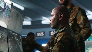 Team of army telecommunications operators using radio and satellite gear, cooperating to provide combat support. Teamworking military dispatchers colleagues managing communications networks, camera A video