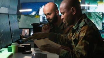 Army officers doing brainstorming in command center, looking at intel folder files. Intelligence corps experts read mission case paperwork to be informed on data on opponents strategy, camera A video