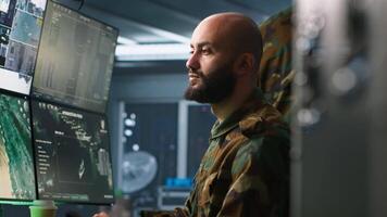 Military agent working in control room, analyzing aerial reconnaissance data. Intelligence corps agent controlling drones attacking strategic targets, camera A video