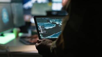 Army telecommunication systems operator using satellite software on tablet, providing combat support. Military dispatcher managing communications networks, with portable device, camera A video
