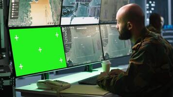 Army soldier looking at chroma key screens in command center housing operational missile defense system designed to intercept ballistic rockets. Specialist using mockup tracking gear, camera A video