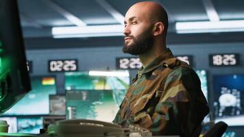 Special forces professional in military HQ base gathering information on enemy troops. Officer using monitoring equipment in base of operations to do assessment of enemy vulnerabilities, camera A video