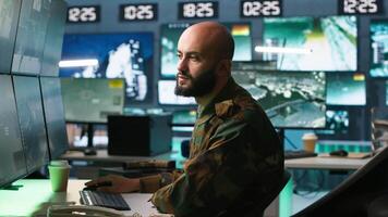 Man looking at screens in military HQ base housing operational missile defense system designed to intercept ballistic rockets. Special forces expert using tracking gear and radar systems, camera A video