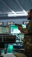Vertical Military soldier wearing camo uniform in mission control center, overseeing national safety operations using laptop. Army expert examining data in monitoring room command center, camera B video