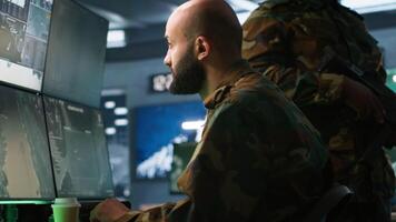 Soldier doing tasks in military base, doing surveillance with digital radar equipment, operating missile systems. Middle Eastern man monitoring army HQ CCTV for any unauthorized activity, camera A video