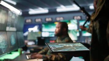 Army operative using tablet in command center housing operational missile defense system designed to intercept ballistic rockets. Close up of expert using tracking software on device, camera B video