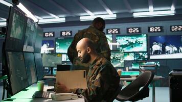 Military officer in command post receiving telephone call while looking at intel files. Intelligence specialist reading opponents strategy mission case file and talking on phone, camera B video