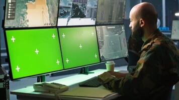 Army specialist working in war room operating surveillance tech, evaluating target data on green screen gear. Man doing job in base of operations, engaging enemy forces using mockup monitors, camera A video