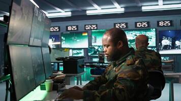 Military agents in war room look at intel folder files on enemy battle formation. Intelligence agency professionals read mission case file to collect data on opponents strategy, camera B video