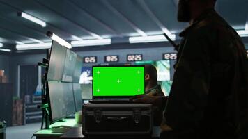 Soldier using tracking software on green screen laptop to gain info against enemies. Army expert using chroma key notebook to gain intel helping troops, coordinating mission activities, camera B video