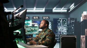 Army expert working in governmental facility operating surveillance tech, evaluating target data. Soldier doing job in HQ base of operations, engage enemy forces, camera B video