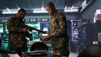 Operatives conducing special operation, doing checkup on rifles and pistols, preparing to attack enemy. African american military units in command post packing guns for assault mission, camera B video
