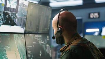 Army telecommunication systems operator using radio and satellite equipment. Middle Eastern military dispatcher managing communications networks, looking at screens, camera A video