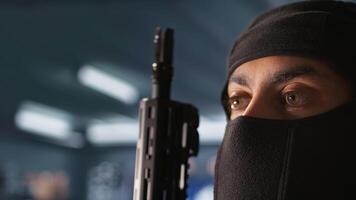 Terrorist hiding identity, attacking enemy command center. Close up of masked insurgent inspecting room during enemy base assault hijacking in guerilla warfare armed conflict, camera B video
