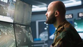 Soldier doing patriotic duty in military HQ base, gathering information on enemy troops. Officer using high tech monitoring gear to do assessment of enemy vulnerabilities, camera A video