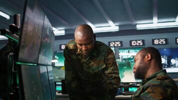 Team of soldiers looking at screens in command center housing operational missile defense system designed to intercept ballistic rockets. Tracking equipment operators using radar systems, camera B video