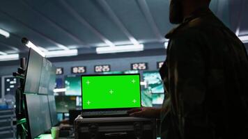 Army specialist working in war room operating surveillance tech, evaluating target data on isolated screen laptop. Soldier engaging enemy forces using chroma key notebook, camera B video