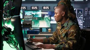 Portrait of military agent working in control room, analyzing aerial reconnaissance data. Intelligence corps agent controlling drones attacking strategic targets, camera B video