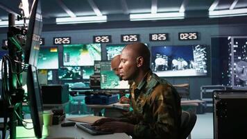 Military dispatcher helped by coworker with tablet to gain info from army intelligence analysts. Army intelligence corps expert discussing with colleague in command post, camera B video