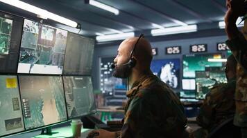 Army specialist working in war room operating surveillance tech, evaluating target data. Close up on dispatcher doing job in HQ base of operations, engaging enemy forces, camera B video