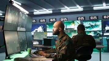 Soldier doing patriotic duty in military HQ base, gathering information on enemy troops. Officer using high tech monitoring gear to do assessment of enemy vulnerabilities, camera B video
