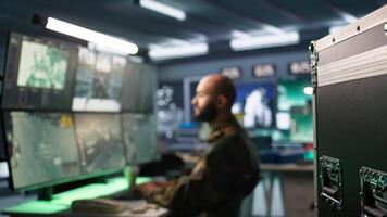 Special forces professional in military HQ base gathering information on enemy troops. Officer using monitoring equipment in base of operations to do assessment of enemy vulnerabilities, camera B video