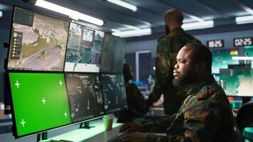 Air force officer performing tactical level surveillance in command room using mockup screen. Military specialist using radar on chroma key gear to look at assault zones, camera B video