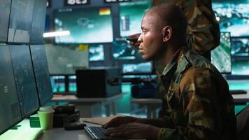 Military dispatcher helped by coworker with tablet to gain info from army intelligence analysts. Army intelligence corps expert discussing with colleague in command post, camera A video