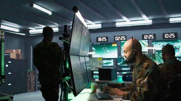 Military dispatcher using headphones microphone, offering info to infantry units fighting on front lines. Army expert providing intel for troops, coordinating mission activities, camera B video