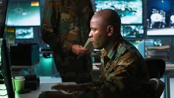 Team of military officers in command center look at intel folder files on enemy battle formation. Intelligence corps colleagues read mission case file to collect data on opponents strategy, camera A video