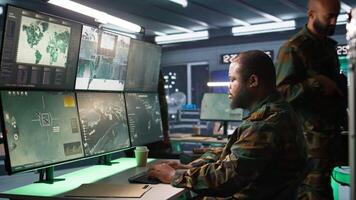 Officer in command center helped by colleague to plan, analyze and gather information on enemy troops. Team of agents in base of operations doing assessment of adversaries vulnerabilities, camera B video