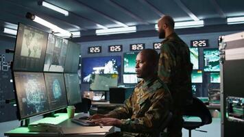 Army professional employing AI tech to improve military combat systems and missiles monitoring. African american IT admin uses neural networks to enhance combat operational capabilities, camera B video