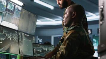 Army colleagues looking at screens in command center housing operational missile defense system designed to intercept ballistic rockets. Experts using tracking gear and radar systems, camera A video