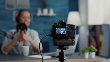 Close up shoot of professional camera recording vlogger talking to audience. Famous social media influencer filming vlog for internet sharing platforms while sitting at home studio desk. video