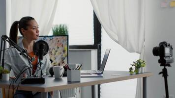 Attractive vlogger sitting at studio desk while starting recording . Popular internet content creator streaming live podcast while looking at modern camera. Studio shoot video