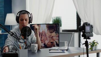 Digital content creator recording in living room studio while tweaking knobs on mixer. Internet live broadcast talk show host talking at microphone with audience while using audio equipment. video