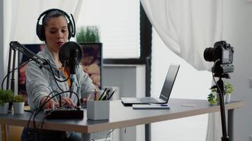Creative content creator recording vlog in home studio while tweaking knobs on audio mixer. Internet live broadcast talk show host talking with audience while using professional audio equipment. video