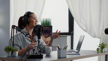 Creative internet influencer putting headphones on while recording blog. Joyful digital content creator starting to record vlog for social media platforms while sitting at home studio desk. video