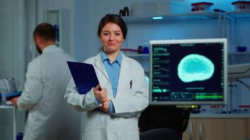 Portrait of scientist neurologist researcher looking at camera smiling while coworker discussing with patient in background about brain functions, nervous system, tomography scan working in laboratory video