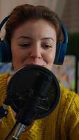 Vertical . Famous woman arranging professional microphone and smiling while recording podcast for social media from home in night. On-air online production internet broadcast show host streaming live content video