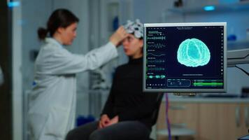 Neurologist doctor analysing nervous system using eeg headset scanning woman brain. Scientist researcher using high tech developing neurological innovation, monitoring side effects on monitor screen video