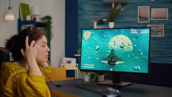 Concentrated gamer puting headset with mic on starting to play space shooter game on virtual competition on powerful pc spending loisure time at home. Esport cyber performing during gaming tournament video